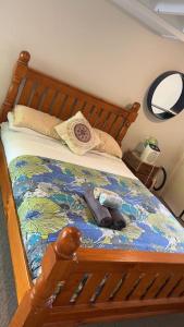 a bed with a wooden frame with towels and shoes on it at 1 Queen Bed and 1 Sofa Bed, Serviced Studio B in Auckland