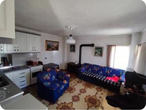 a living room with a blue couch and a kitchen at Guest House MITRE in Pusteci