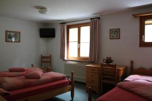a bedroom with two beds and a dresser and a window at Hotel Foppoli in Poschiavo
