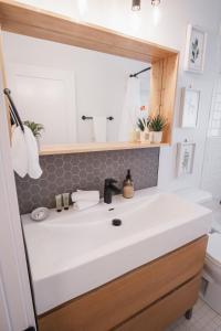een badkamer met een witte wastafel en een spiegel bij Play & Stay - Downtown Sleeps 10 in Edmonton +63 foto's