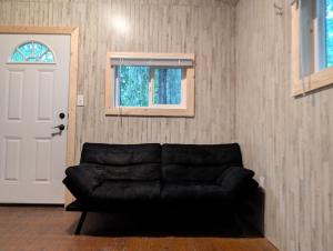 a black leather couch in a living room with a door at Sven's Basecamp Hostel in Fairbanks