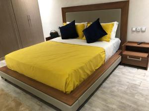 a bedroom with a large bed with a yellow bedspread at Eden Prestige in Bouznika