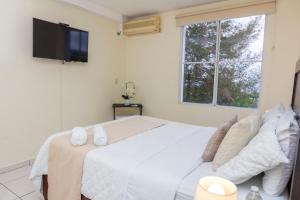 a bedroom with a white bed and a flat screen tv at Luxury Modrn Apartment, w/amazing view, 3BR,Escalon,Exclus,Secur in San Salvador