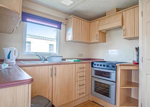 a kitchen with wooden cabinets and a stove top oven at Woodland Vale Holiday Park in Ludchurch
