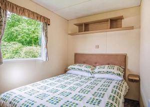 a bed in a small room with a window at Woodland Vale Holiday Park in Ludchurch +26 photos