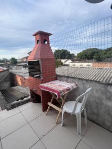 a brick oven with a table and a chair on a roof at Casa simples e confortavel, próx ao centro de pelotas in Pelotas