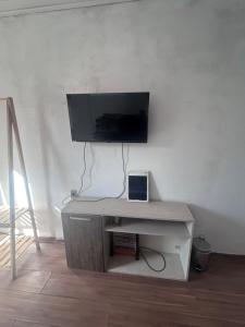 a white desk with a tv and a laptop on it at Casa simples e confortavel, próx ao centro de pelotas in Pelotas