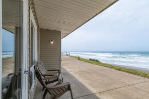 two chairs sitting on a porch looking at the beach at Pool and Hot Tub Ground Floor Studio - Oceanfront - Full Kitchen - Patio in Lincoln City