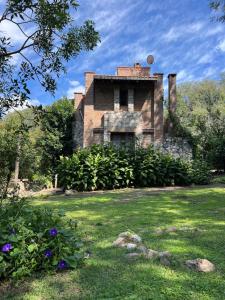 ein altes Backsteinhaus in einem Hof mit Blumen in der Unterkunft Las Camellias in La Cumbre + 20 Fotos