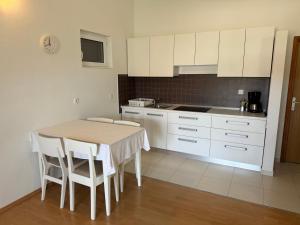 a kitchen with white cabinets and a table and chairs at Apartment Palit 16356b in Mundanije