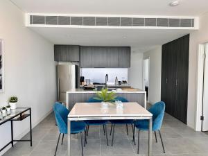 a kitchen and dining room with a table and blue chairs at Luxurious city view at Sydney Olympic Park in Sydney +29 photos