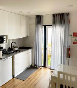 a kitchen with white cabinets and a door to a patio at Lugar da Praia - Consolação - Peniche in Peniche