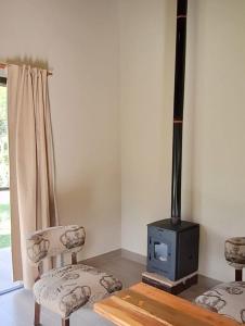 a living room with a stove and two chairs at Barcena Houses in Tumbaya