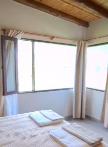 a bedroom with two towels on a bed with two windows at Barcena Houses in Tumbaya