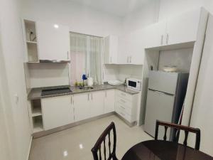 a kitchen with white cabinets and a table and chairs at Vivenda Paraíso, Charming house on the Plateau in Praia
