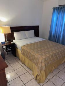 a bedroom with a bed with blue curtains and a table at bamboo bed and breakfast in San Pedro Sula