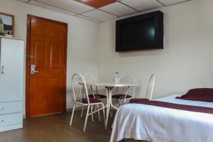una habitación con una cama, una mesa y sillas en El Centro Hotel, en Quetzaltenango