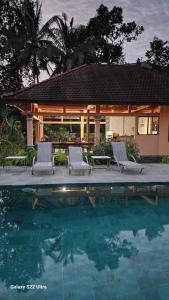 a swimming pool with two chairs and a house at The Mungseng Villa Bali in Singaraja