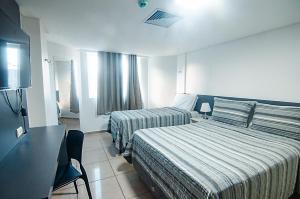 a hotel room with two beds and a television at Flat de frente à praia in João Pessoa +18 photos
