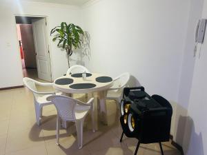 ein weißer Tisch und Stühle mit einer Tasche auf dem Boden in der Unterkunft Hermoso Depto in La Playa Bejarano