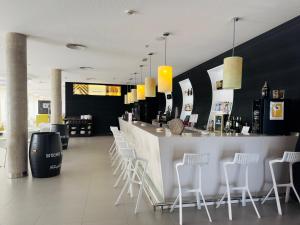 un restaurante con un bar con sillas blancas en Hotel Palacio Albacete & SPA, en Albacete