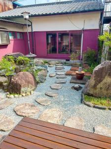 ein Garten mit Felsen und einer Bank vor einem Haus in der Unterkunft 癒しの宿 Villa ZEN 讃岐白鳥 in Higashikagawa