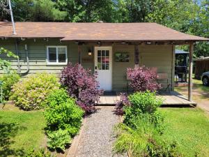 a small house with a porch with purple flowers at Pine Ridge Park Campground in Pembroke