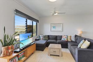 a living room with a couch and a large tv at Luxe Ocean View Retreat - Acutterbove Straddie in Point Lookout