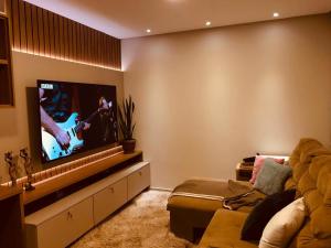 a living room with a couch and a flat screen tv at Linda casa - 03 quartos - perto do centro in Garanhuns