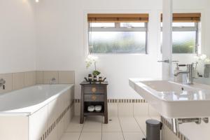 a white bathroom with two sinks and a tub and a bath tub at Sanctuary 53 Beautiful Views in Taupo +26 photos