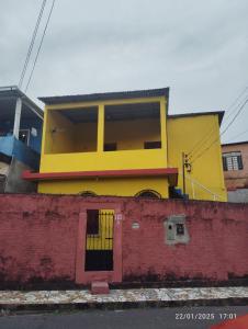 a yellow building behind a red wall at Quarto em casa compartilhada in Manaus