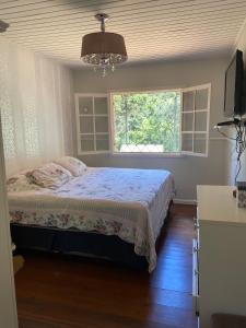 a bedroom with a bed and a window at Refúgio das Araucárias in Campos do Jordão