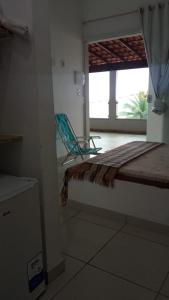 a room with a chair and a bed and a window at Suites de frente pra praia in Itapemirim