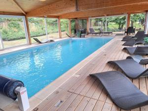 a swimming pool with chairs on a wooden deck at Holiday Farm by Red River with Indoor Pool in Pfaffenhoffen