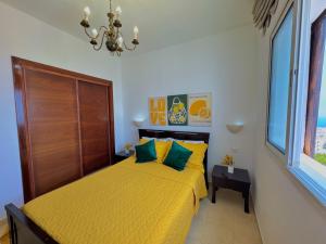 Un dormitorio con una cama amarilla y una lámpara de araña. en Appartement vue panoramique sur mer à BELLA VISTA, en Cabo Negro