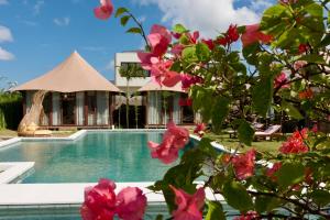 a resort with a swimming pool and pink flowers at Wildflower Events in Uluwatu