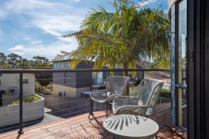 a balcony with two chairs and a table and a palm tree at Perfect Jervis Bay location & fresh modern living in Vincentia