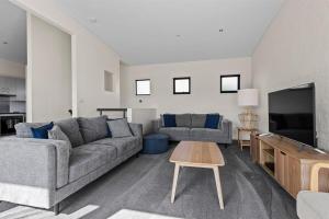 a living room with a couch and a tv at Perfect Jervis Bay location & fresh modern living in Vincentia +12 photos