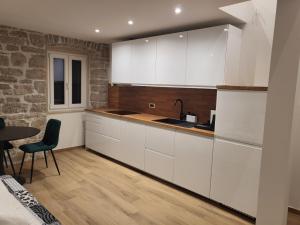 a kitchen with white cabinets and a table at Old town Bol apartments in Bol