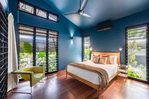 a bedroom with blue walls and a bed and a chair at Tropic Pavilion - Breezy Designer Retreat near Beach in Paraparap +51 photos