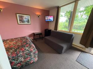 a bedroom with a bed and a chair and a tv at Motel Le Voyageur in Saint-Jérôme