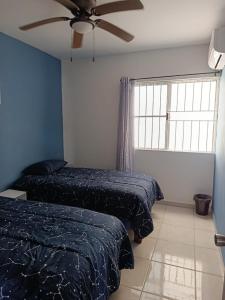 a bedroom with two beds and a ceiling fan at Depto Vacacional Playa in Ciudad Madero