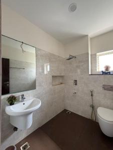 チェンナイにあるWater's egde service apartmentの洗面台、トイレ、鏡のあるバスルーム