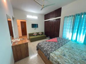a bedroom with a bed and a desk and a couch at RITU CAPITOL Homestay in Trivandrum