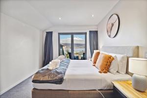 a bedroom with a large bed with a large window at Lakefront Living - 4 Bedrm Apartment Alpine Village in Queenstown