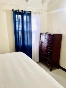 een slaapkamer met een bed, een dressoir en een raam bij Resort Vibes Getaway - Colbeck Manor Old Harbour - Gated, pool, gym in Old Harbour