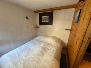 a small bedroom with a bed and a wooden door at Appartement T4 Duplex 60m², 6 Pers, Vue Lac & Montagnes - FR-1-758-40 in Les Angles