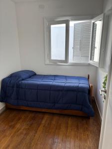 a bedroom with a blue bed in a room with a window at Depto 2 dormitorios a 5 min Parque San Martin in Mendoza
