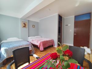 a bedroom with two beds and a table and chairs at Hotel El Sol de Carhuaz in Carhuaz