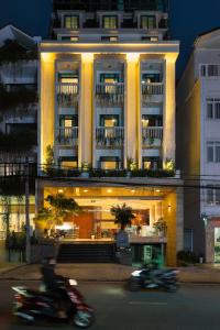 a building with people riding motorcycles in front of it at Celine Express - Q Dalat Hotel in Da Lat